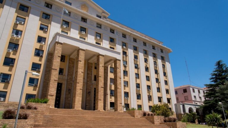 Personas realizando una intervención simbólica de color rojo frente a la Casa de Gobierno de Mendoza.
