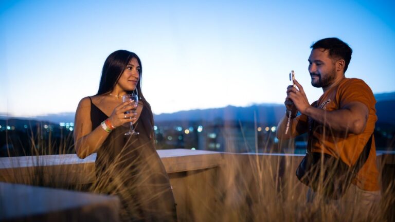Grupo de personas realizando un brindis durante la experiencia 'Brindemos' en la Ciudad de Mendoza, con copas de vino en primer plano.