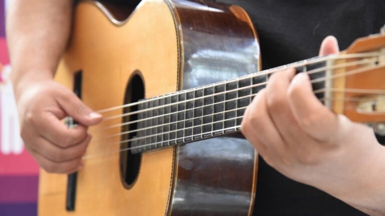 Persona tocando una guitarra criolla en un taller musical.