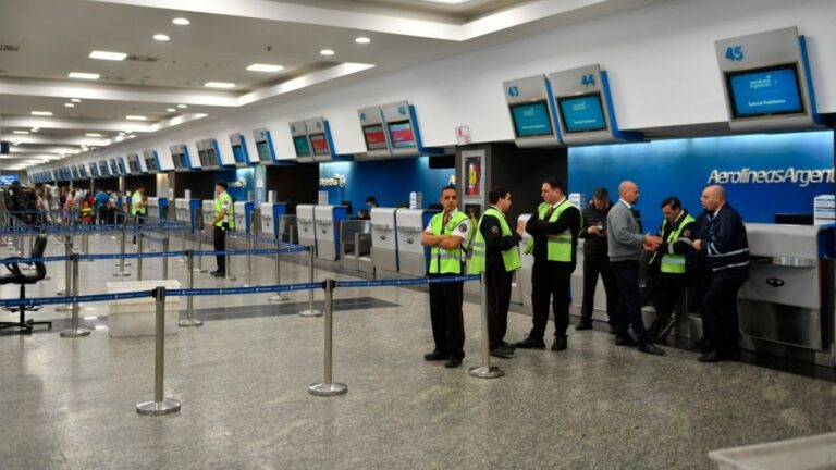 Pasajeros consultando pantallas de información de vuelos en un aeropuerto.